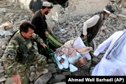 An Afghan security member and people carry an injured man after a suicide attack in Zabul on September 19.