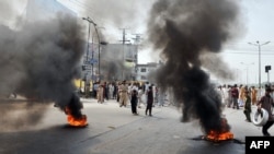 Demonstrators gather behind burning tires as they block a main highway during a protest in Rawalpindi on September 21.