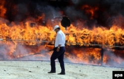 An Iranian policeman walks past a cloud of smoke rising from a pile of drugs that was set on fire during an incineration ceremony for some 50 tons of illicit narcotics seized by the authorities. (file photo)