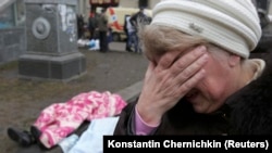 A woman reacts as dead bodies are seen on the ground following violence on Independence Square.