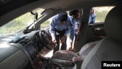 Police collect evidence from the car in which Chaudhry Zulfikar was traveling when he was attacked.