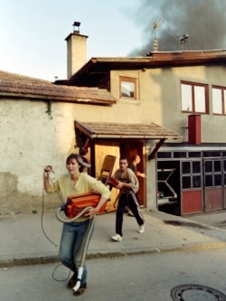 Civilians in Sarajevo flee with their possessions after a mortar shell set their home ablaze in September 1992.