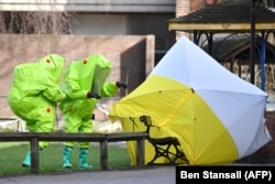 Investigators in green bio-hazard suits examine the site where Sergei Skripal and his daughter Yulia were found poisoned in Salisbury, England, earlier this year.