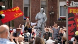 MLPD leader Gabi Fechtner (right, in gray) sings the Internationale next to the Lenin monument.