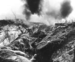 U.S. Marines duck for cover as mortars burst near their trench.