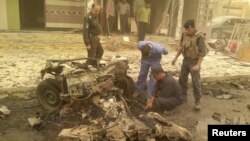 Iraqi security personnel inspect the site of a car bomb attack in the city of Ramadi on 19 April.