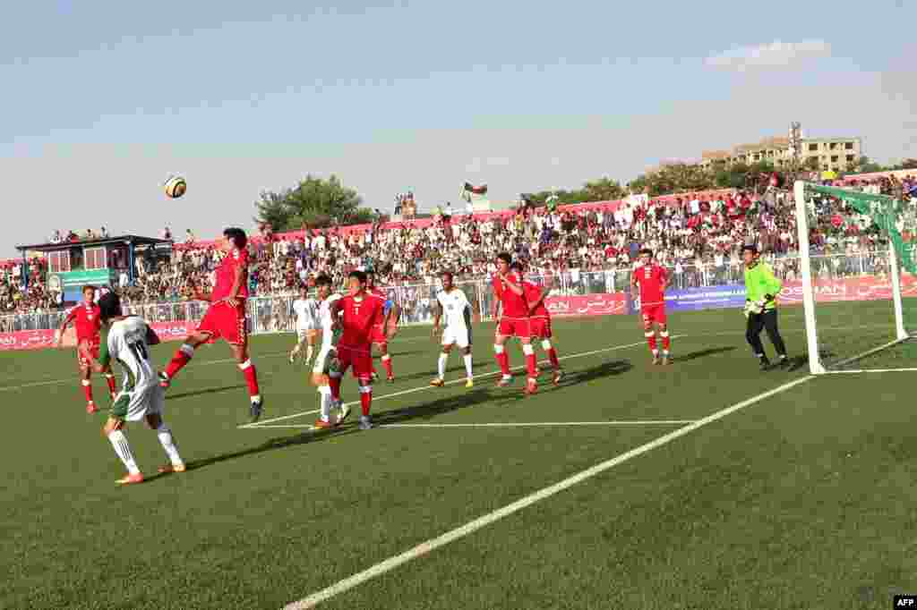 An Afghan player (in red) heads the ball away during the match.