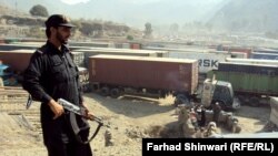 A Pakistani security officer stands guard over long lines of NATO trucks and oil tankers at a border crossing amid a blockade against NATO vehicles transporting supplies to Afghanistan via Pakistan. The blockade has been in place since November 26, when 2