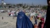 A burqa-clad woman stands by a displacement camp in Kabul on September 17.