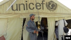 An Afghan policeman stands guard outside a polling station, in Kandahar, where there were reports of Taliban attacks in the city.