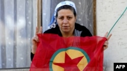 A Kurdish woman waves a PKK flag from her house in Diyarbakir, Turkey. 