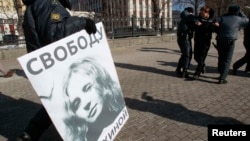 Police officers remove a placard and detain a supporter of jailed members of the punk group Pussy Riot during a protest calling for their release, held in central Moscow, on March 8.