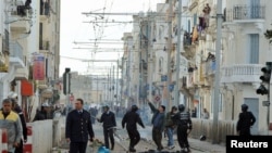 Riot police and rioters on a main square in the capital, Tunis, on January 13