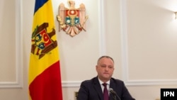 A file photo of Moldovan President Igor Dodon with the country's current tricolor flag in the background.