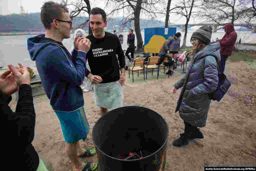 Participants warm up by a fire after taking their cold swim.