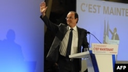 Socialist Party candidate Francois Hollande waves on stage following early vote results in Tulle.