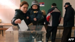 A Kosovo Serb woman with her child casts her ballot at a poling station in Kosovska Mitrovica on February 15.