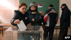 A Kosovar Serb woman with her child casts her ballot at a polling station in Kosovska Mitrovica.