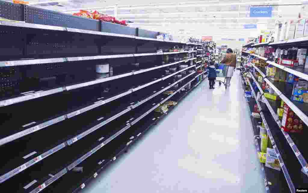 A woman and child walk through an aisle, emptied in preparation for Hurricane Sandy, in a Wal-Mart store in Riverhead, New York.&nbsp;