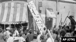 A crowd of demonstrators tear down the Iran Party's sign from the front of the headquarters in Tehran on August 19, 1953, during the pre-Shah riot that swept through the capital and ousted Prime Minister Mohammad Mossadegh.