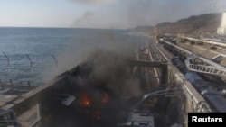 Fire and smoke billow on April 12 at a building for sampling seawater near the No.4 reactor of TEPCO's Fukushima Daiichi Nuclear Power Plant.