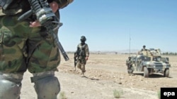 Afghan soldiers guard the area as President Hamid Karzai visits the scene of the air strike