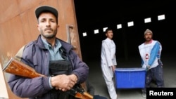 Afghan Election Commission workers carry a ballot box as a police officer stands guard at a warehouse in Herat on April 3.