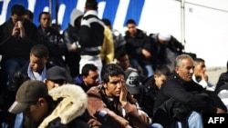 Tunisian immigrants who arrived on the Italian island of Lampedusa wait to board a boat for temporary accomodation on February 17.