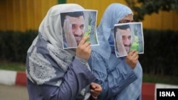 Two women cover their faces with images of Mahmud Ahmadinejad. (file photo)