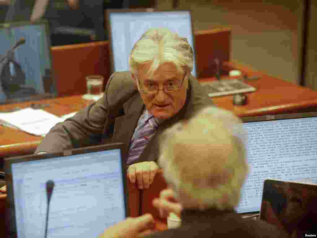 Former Bosnian Serb leader Radovan Karadzic talks to his defense team in a courtroom at the ICTY.