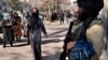 Afghan women pass by a Taliban fighter on a street in Kabul.