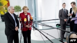 German Chancellor Angela Merkel (right) and International Monetary Fund chief Dominique Strauss-Kahn speak to journalists after a meeting in Berlin.