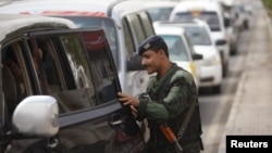 A police trooper checks a car at a checkpoint on the road leading to Sanaa International Airport on August 6.