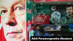 A Pakistani vendor sits next to images of Imran Khan at a market in Islamabad on July 27.