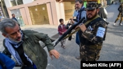 A Taliban fighter pushes a journalist covering a demonstration by women protesters outside a school in Kabul on September 30, 2021.