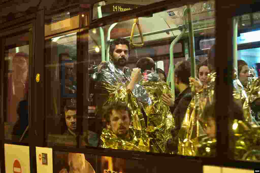 Survivors of the Bataclan theatre massacre wear emergency thermal blankets as they are evacuated by bus from the scene of the attack.