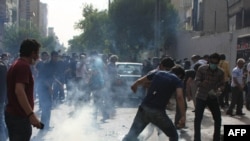 Protesters battle tear gas fired by police during a rally in Tehran on July 9.