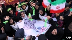 Iranian women hold an anti-U.S. sign, bearing a cartoon of U.S. President Barack Obama, outside the former U.S. Embassy in Tehran on November 2.