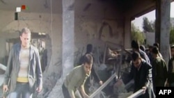 A screengrab from Syrian state TV shows people searching through rubble at the site of an apparent suicide attack at a security service base in Damascus.