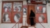 A woman wearing a niqab enters a beauty salon where the ads of women have been defaced by a shopkeeper in Kabul.
