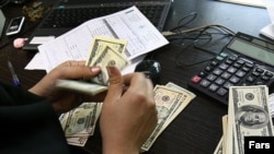 A woman counts US dollars banknotes in a currency exchange office in Tehran