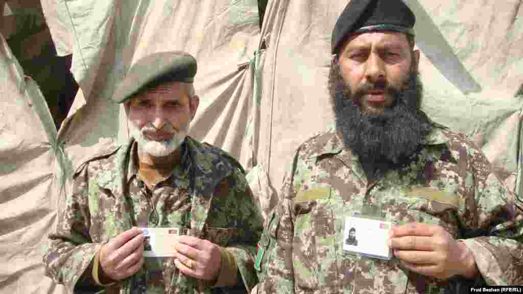 Two Afghan soldiers show off their new voter cards.