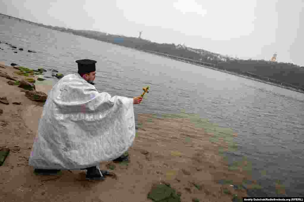 A military chaplain sanctifies the waters of the Dnieper River in honor of Ukrainian soldiers.