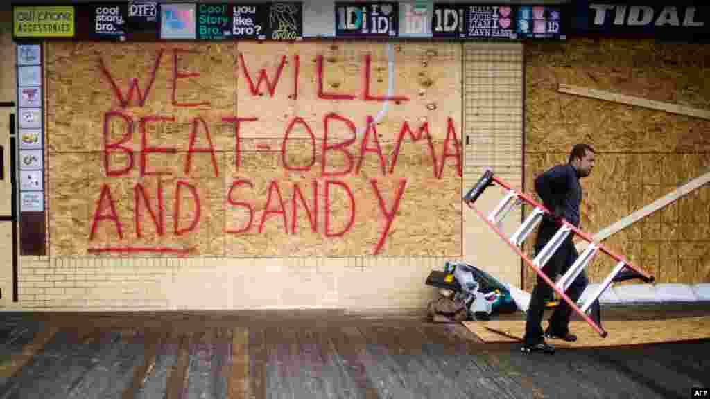 Raymond Souza carries away a ladder after boarding up Tidal Rave&#39;s 5 &amp; 10 gift shop on the boardwalk ahead of Hurricane Sandy&#39;s landfall in Rehoboth Beach, Delaware.&nbsp;