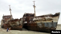 Children run past ruined ships abandoned in sand that once formed the bed of the Aral Sea. Lake Balkhash in Kazakhstan faces the danger of becoming another Aral Sea because of upstream diversion by China.