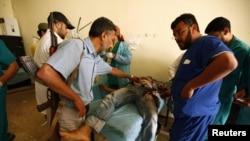 A Libyan rebel fighter stands as medics treat an injured rebel fighter at a field hospital near Misurata's western front line on June 8.