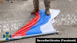 A soldier from Ukraine's Security Service stands on a Russian flag in the city of Kupyansk, Kharkiv region, on September 10.