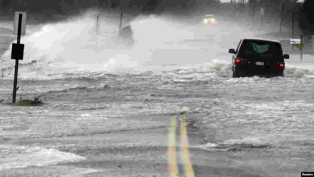 A car drives through water driven onto a roadway by Hurricane Sandy in Southampton, New York.