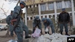 Afghan policemen stand next to packages containing opium during a police presentation in Herat in December.