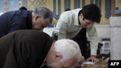 Iranians scrutinize their ballots at a polling station in Tehran on June 12.